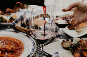 Glass of red wine being poured at dinner table